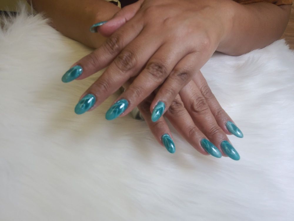 Glossy teal cat eye gel almond-shaped nails on a soft white fur background