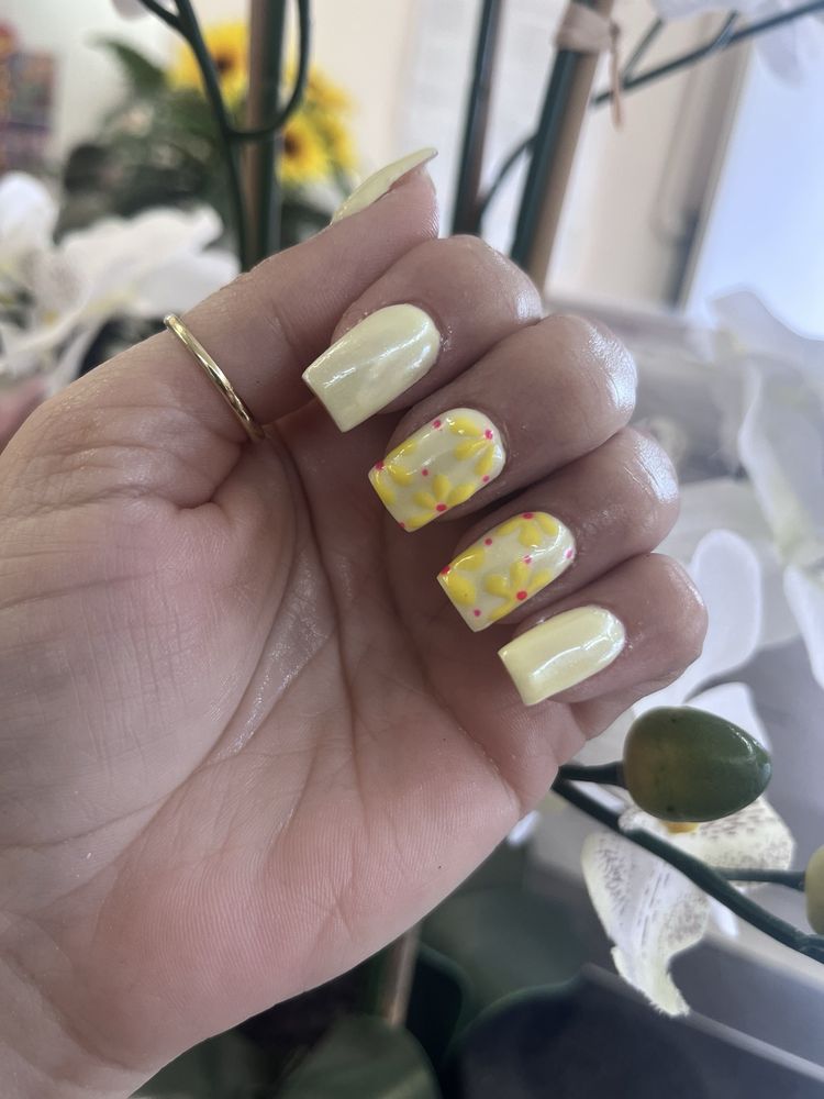 Buttery yellow nails with hand-painted yellow daisies and pink dots